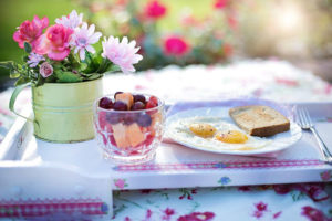 Breaksfast table with the meal and a vase of flowers