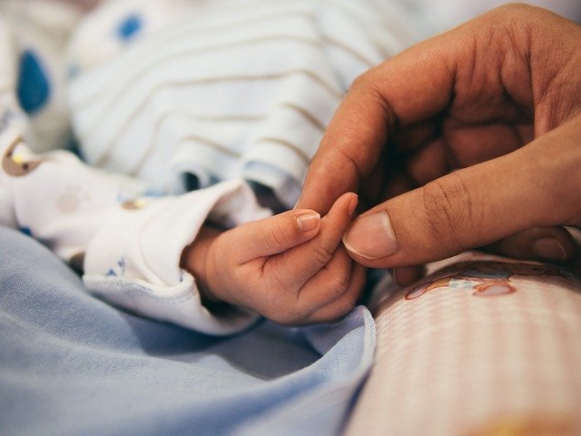 Mother's hand holding or touching the hand of her baby