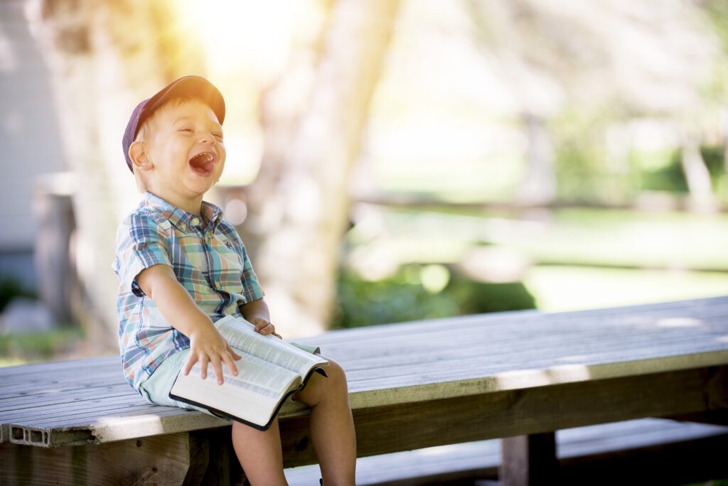 happy boy laughing with open book on lap