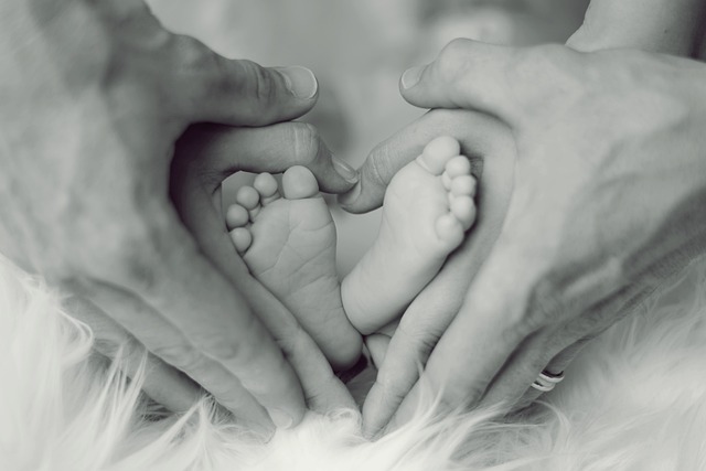 Infant feet surrounded by the hands of his parents forming concentric hearts